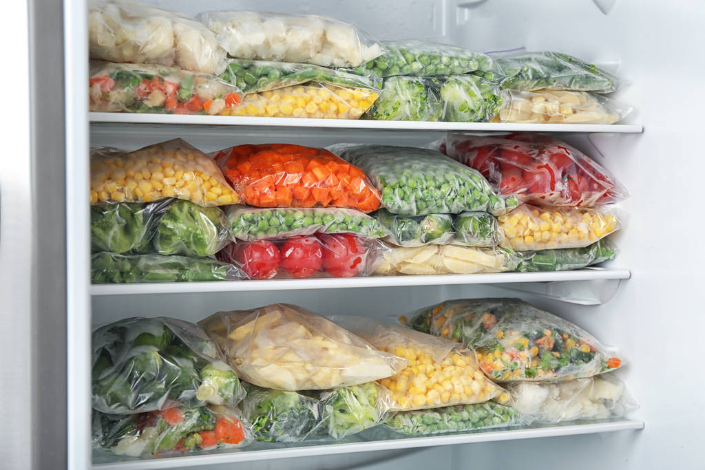 Plastikowe torby z różnymi mrożonymi warzywami w lodówce - Zdjęcie, obraz