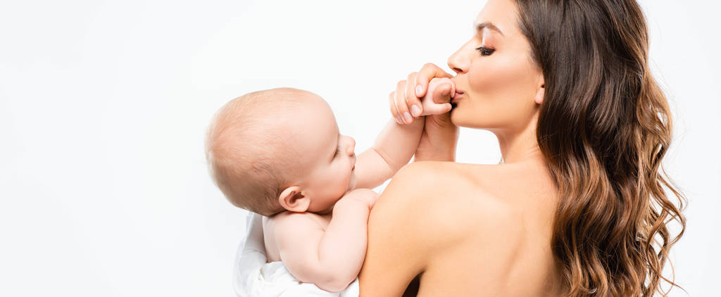 Panoramaaufnahme einer glücklichen nackten Mutter, die die Hand eines kleinen Jungen küsst, isoliert auf Weiß - Foto, Bild