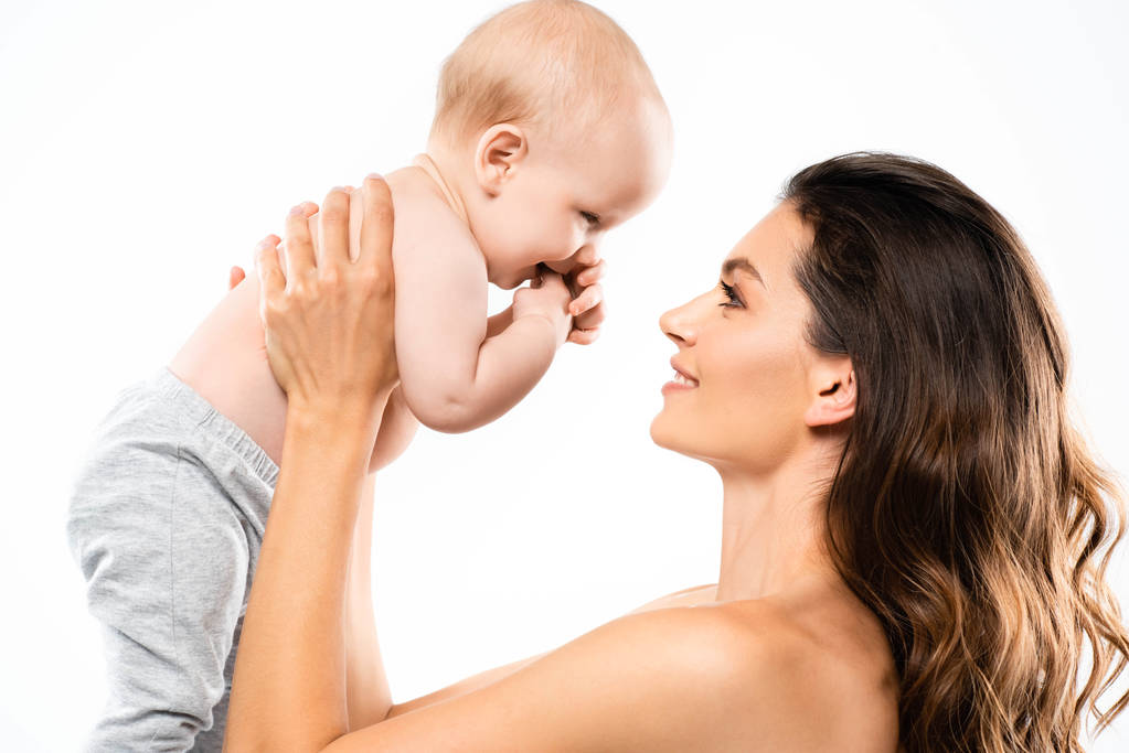 portrét nahé usměvavé matky dívající se na dítě, izolované na bílém - Fotografie, Obrázek