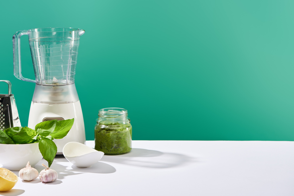 salsa di pesto, ingredienti e utensili da cucina su tavolo bianco isolato su verde
 - Foto, immagini