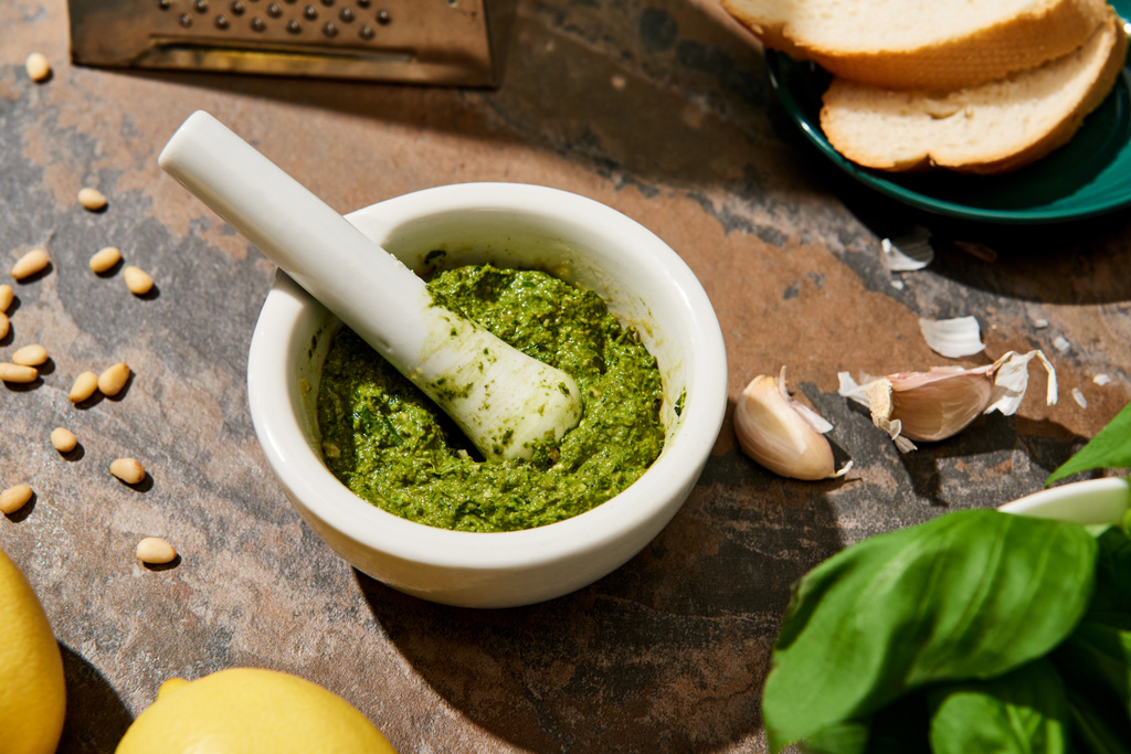 Baguette-Scheiben, Pesto-Sauce im Pfund und frische Zutaten auf Steinoberfläche - Foto, Bild