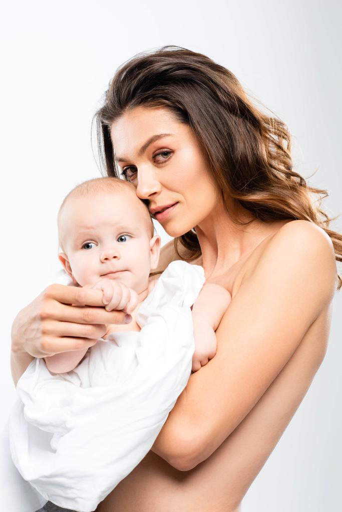 πορτρέτο της γυμνής μητέρας κρατώντας το μωρό και κοιτάζοντας κάμερα, απομονωμένη σε λευκό - Φωτογραφία, εικόνα