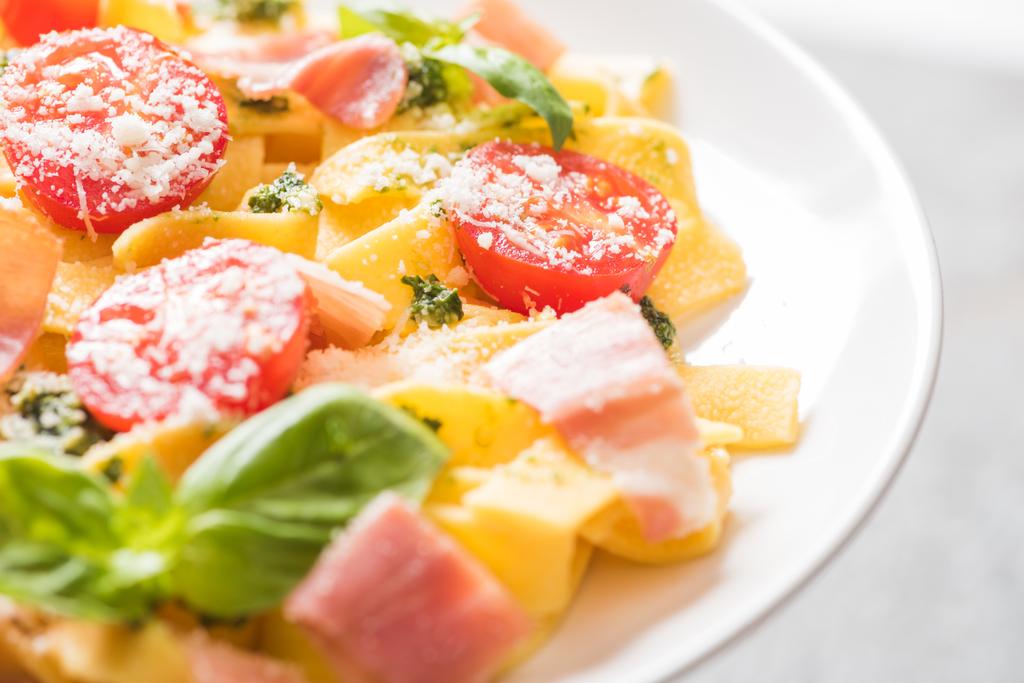 Nahaufnahme köstlicher Pappardelle mit Tomaten, Parmesan, Pesto-Sauce, Basilikum und Prosciutto - Foto, Bild