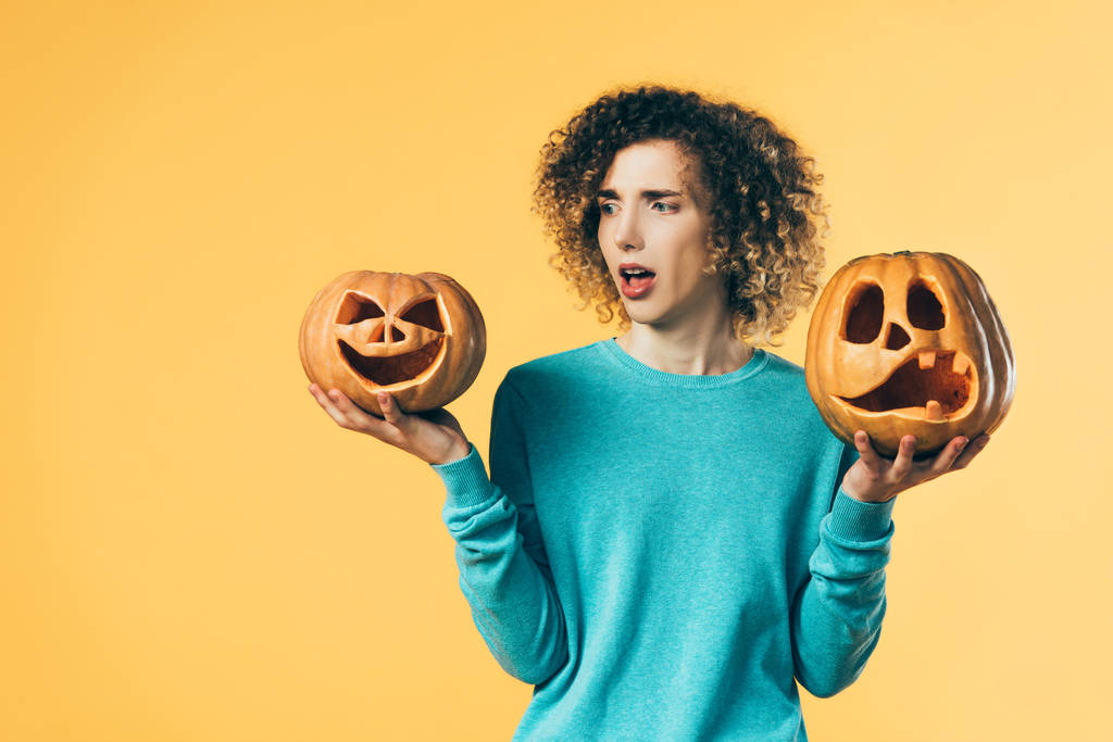 rémült göndör tinédzser nézi Halloween tök elszigetelt sárga - Fotó, kép
