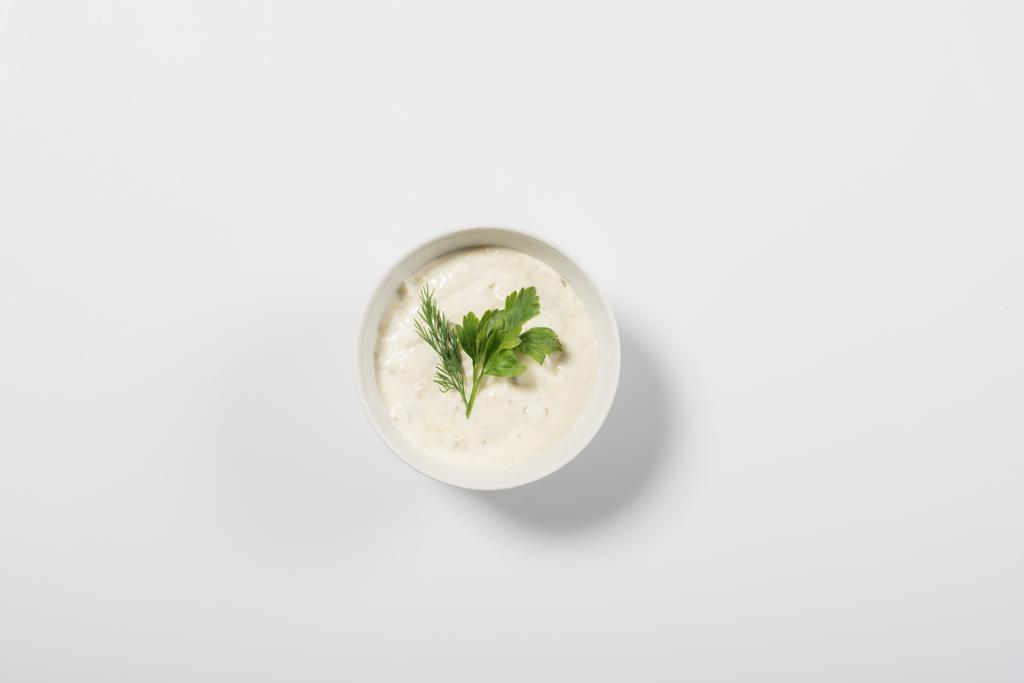 Vista dall'alto di gustosa salsa tzatziki con verde su sfondo bianco
 - Foto, immagini
