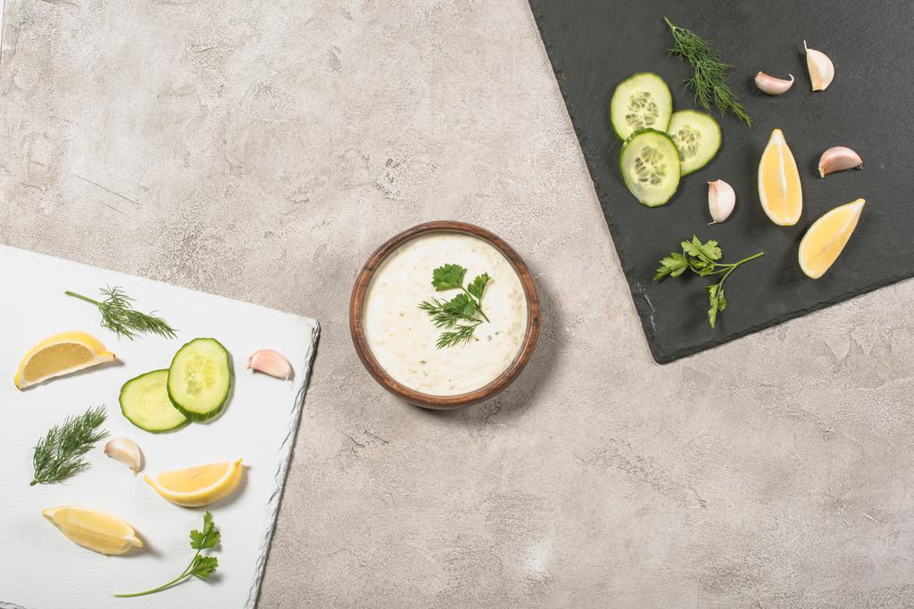 Top view of tzatziki sauce with fresh ingredients on boards on stone background - Photo, Image