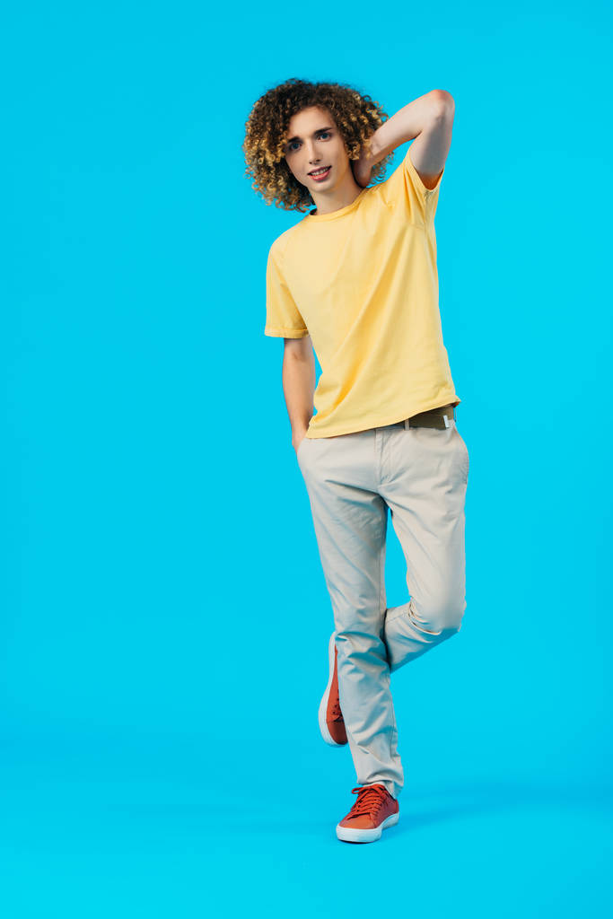 full length view of curly teenager posing isolated on blue - Photo, Image