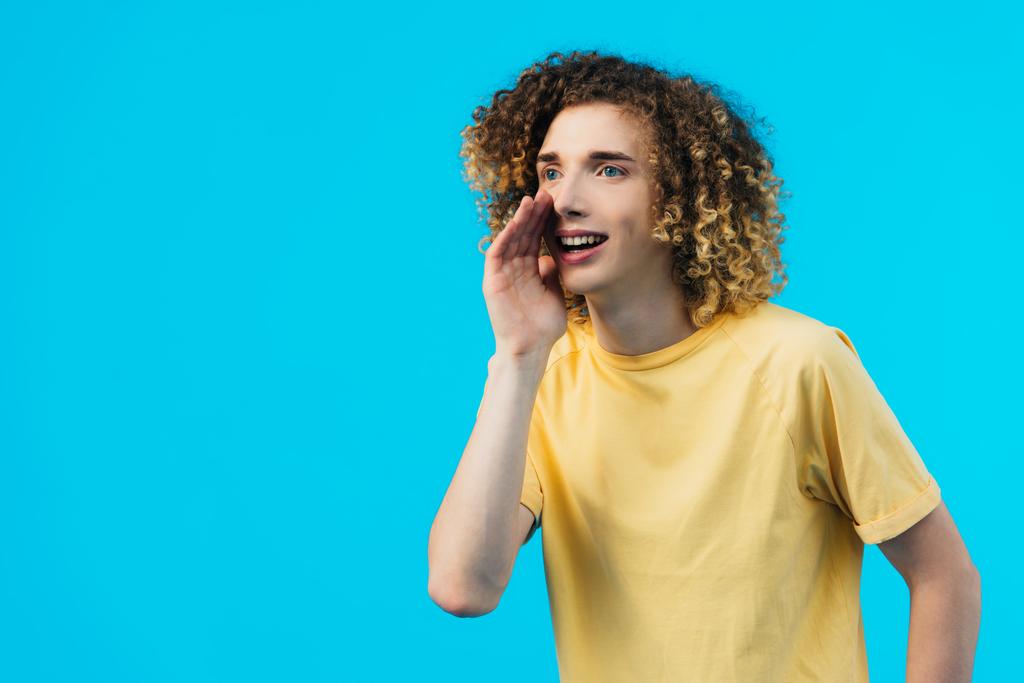 Lächelnder lockiger Teenager tratscht isoliert auf blauem Grund - Foto, Bild