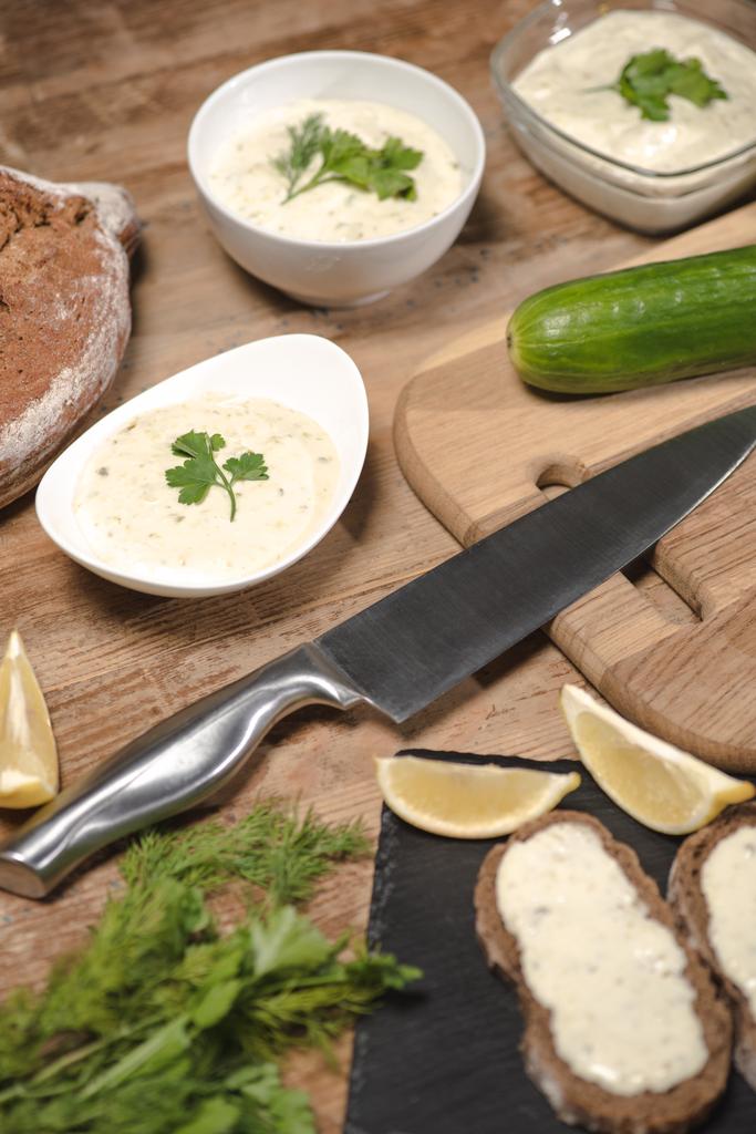 leckere hausgemachte Tzatziki-Sauce mit Brot und Grün auf Holztisch  - Foto, Bild