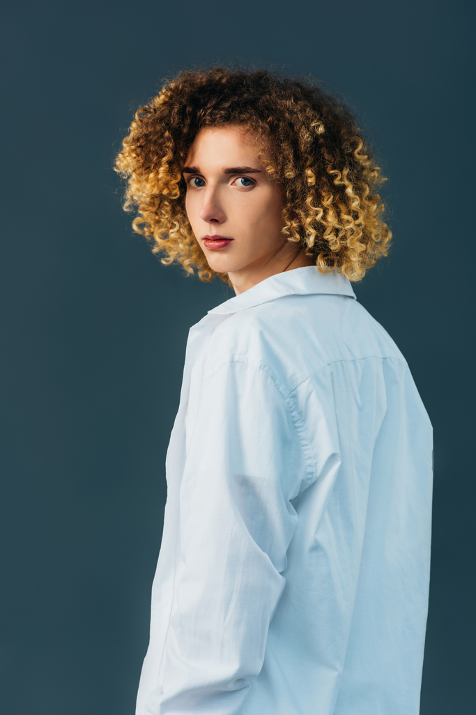 back view of curly teenager in total white outfit isolated on green - Photo, Image