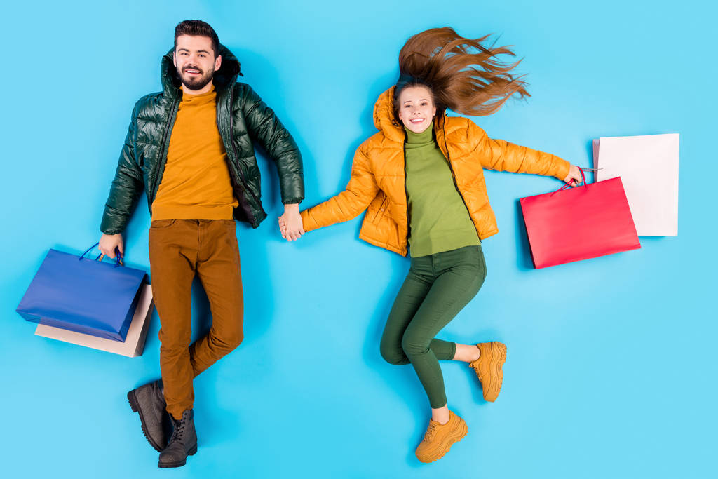 Full length body size top above high angle view photo of cheerful cute fun positive nice couple of casual people looking at you with packages in hands isolated pastel blue color background - Zdjęcie, obraz