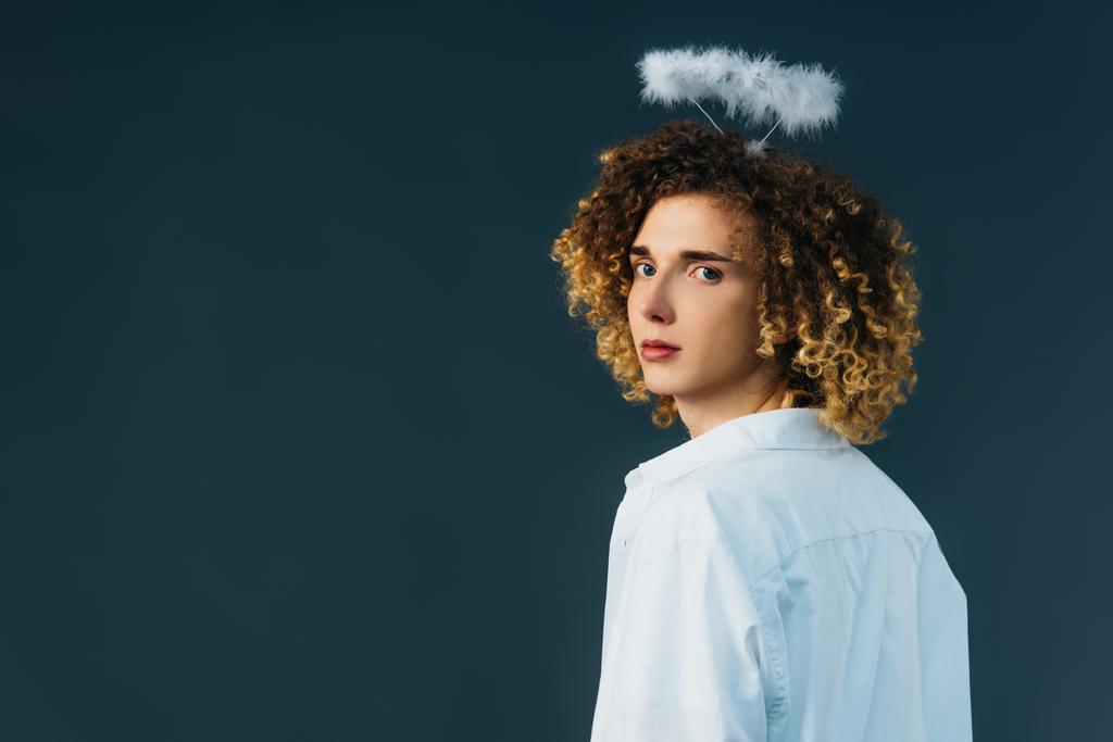 back view of curly teenager in angel costume with halo above head isolated on green - Photo, Image