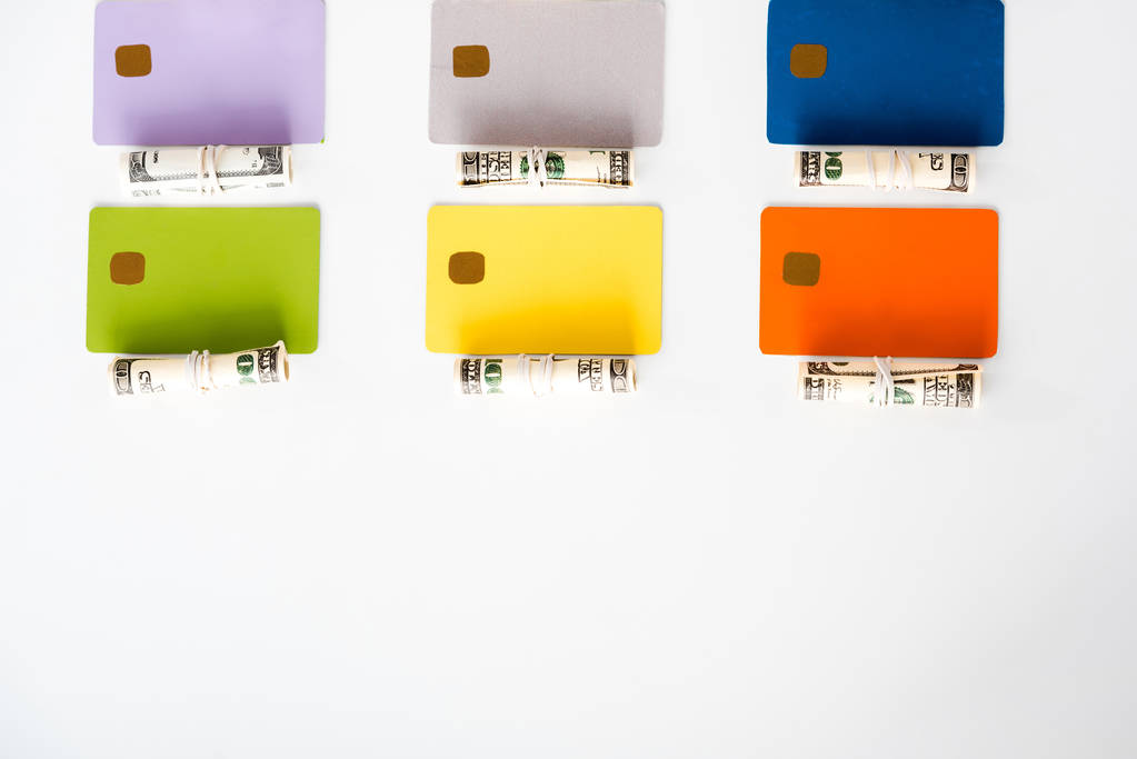 現金ロールの近くのカラフルなクレジットカードテンプレートのトップビューと白で隔絶されたドル紙幣  - 写真・画像