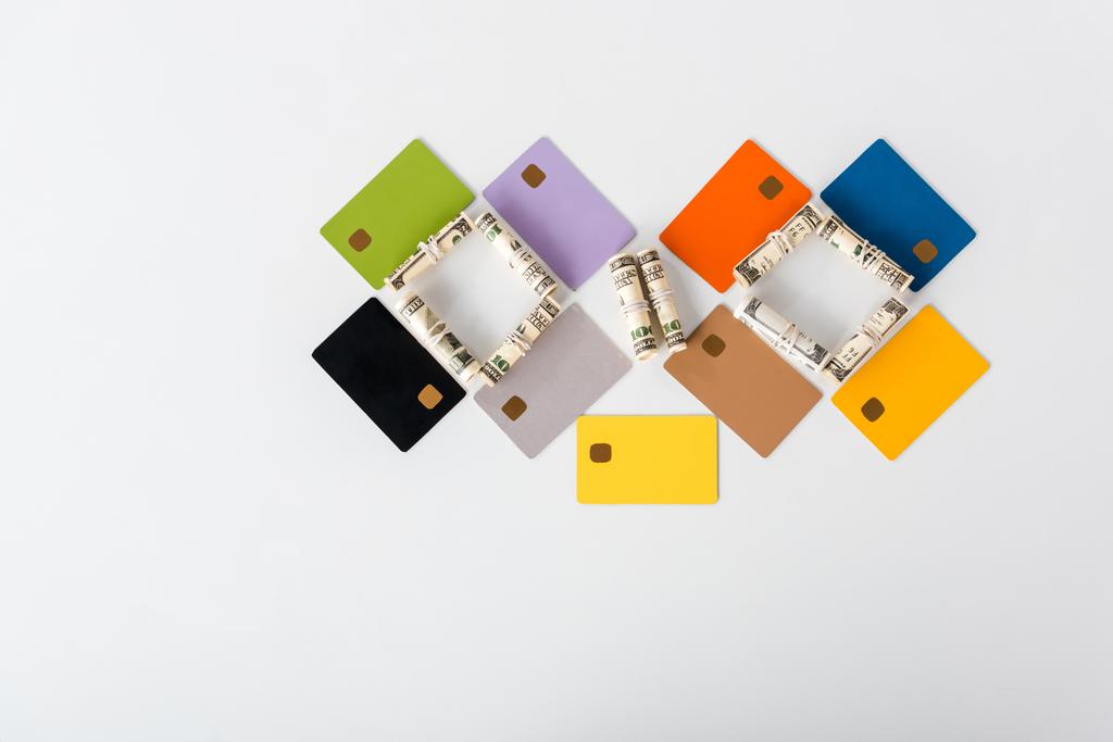 ylhäältä näkymä värikäs luottokortin malleja säästöjä lähellä käteistä rullina valkoinen
  - Valokuva, kuva
