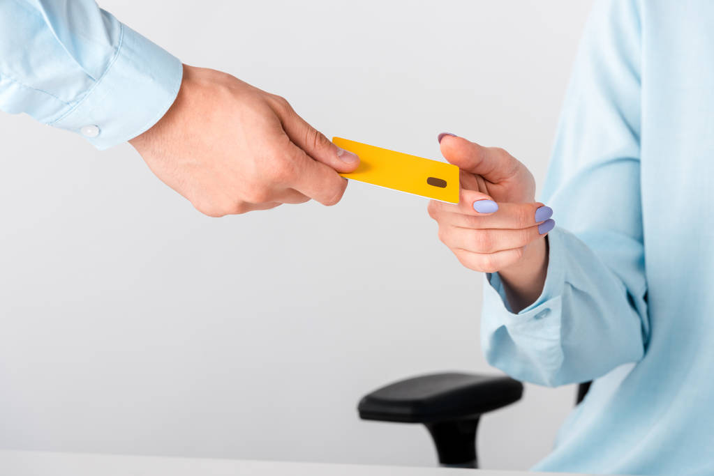 abgeschnittene Ansicht eines Mannes, der Frau eine gelbe Kreditkartenvorlage gibt, isoliert auf Weiß  - Foto, Bild