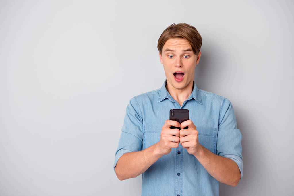 Послідовники Omg. Дивовижний хлопець використовує свій смартфон, читаючи новини соціальної мережі крик неймовірний одяг модний одяг ізольований на сірому кольоровому фоні
 - Фото, зображення