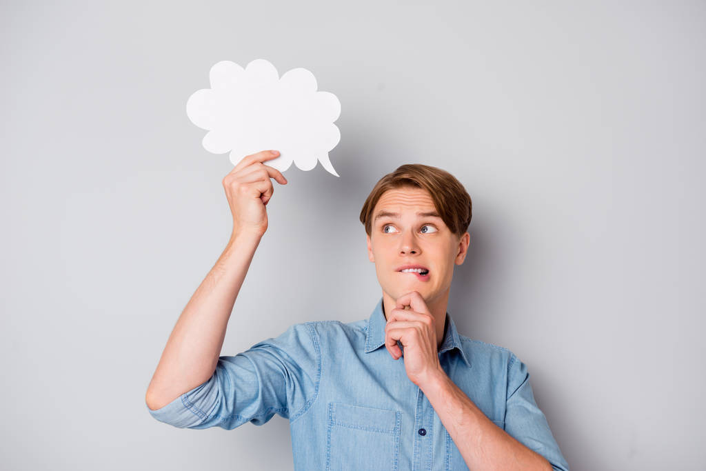 Portrait of minded troubled guy hold white paper card bubble think thoughts hesitate solution bite lips touch chin wear good looking outfit isolated over grey color background - Photo, Image