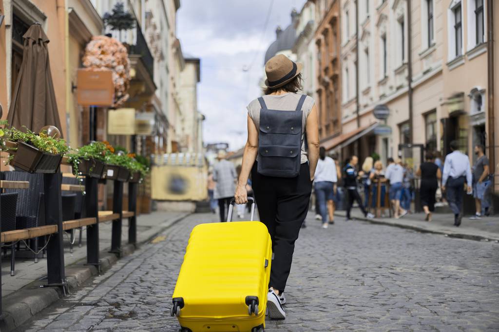Turista mujer viajera en sombrero con mochila y maleta caminando
 - Foto, imagen