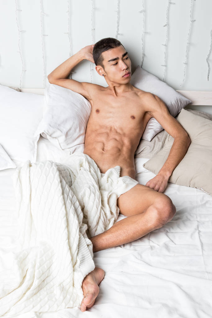Joven hombre guapo descansar en la cama. Sexy chico desnudo está descansando
 - Foto, Imagen