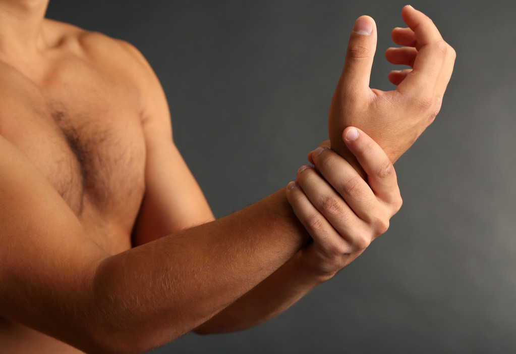 νεαρός άνδρας με πόνος χεριών σε γκρι φόντο - Φωτογραφία, εικόνα