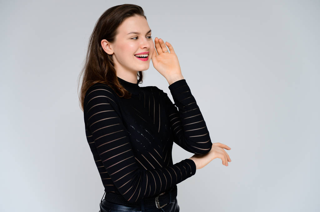 Concept adult girl on a white background. Large photo of a pretty brunette girl in a black sweater smiling and showing different emotions in different poses right in front of the camera. - Photo, Image
