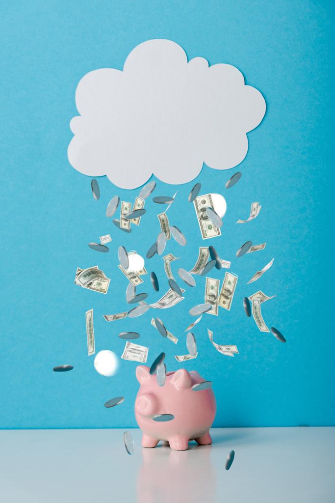 рожевий скарбничка біля білої хмари і падаючі гроші на синій
  - Фото, зображення