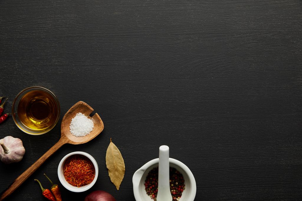 Ansicht von Gewürzen, Salz und Olivenöl auf schwarzem Holzhintergrund - Foto, Bild