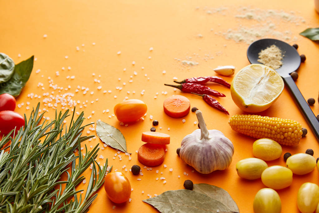 Fresh rosemary with vegetables and spices on orange background - Photo, Image