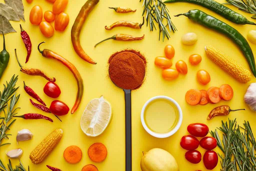 Bovenaanzicht van biologische groenten en kruiden met chili kruiden op gele achtergrond - Foto, afbeelding