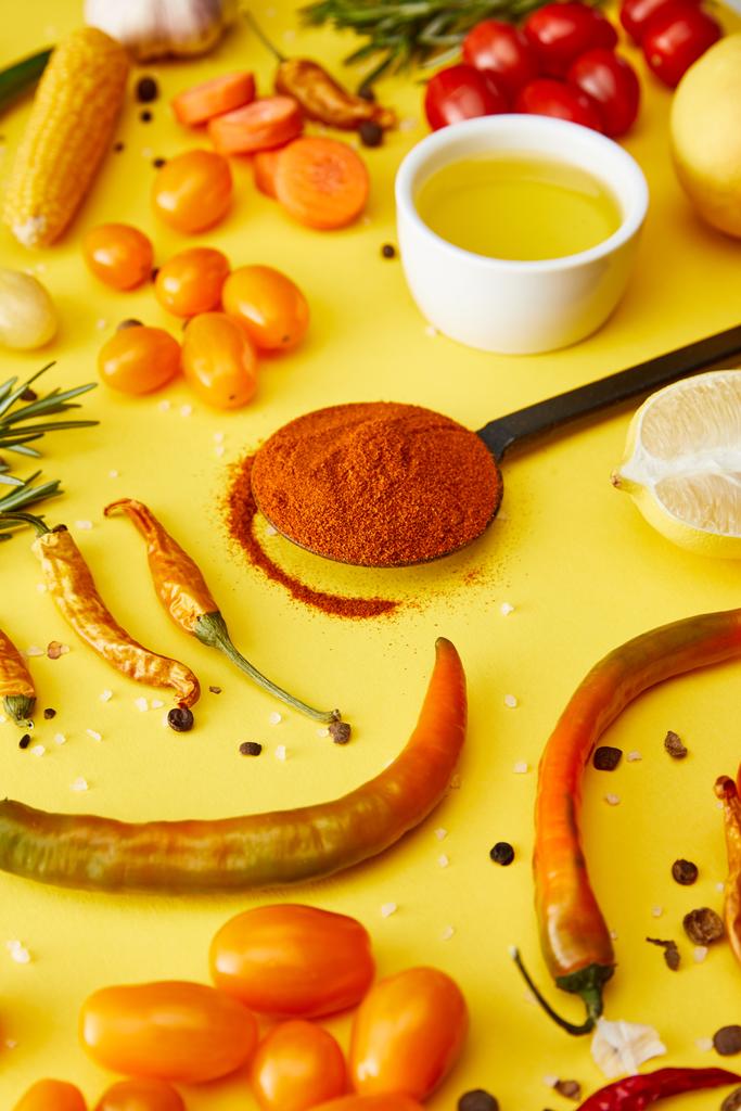 Επιλεκτική εστίαση του μπαχαρικού τσίλι στο κουτάλι με βιολογικά λαχανικά σε κίτρινο φόντο - Φωτογραφία, εικόνα