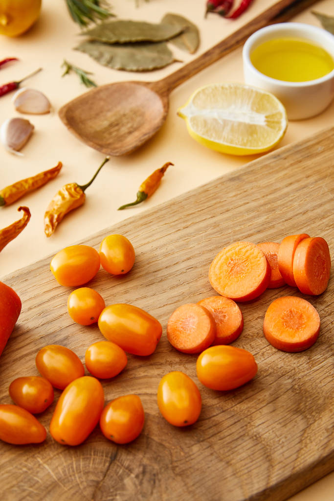 Селективный фокус свежих овощей на разделочной доске со специями и оливковым маслом на бежевом фоне
 - Фото, изображение