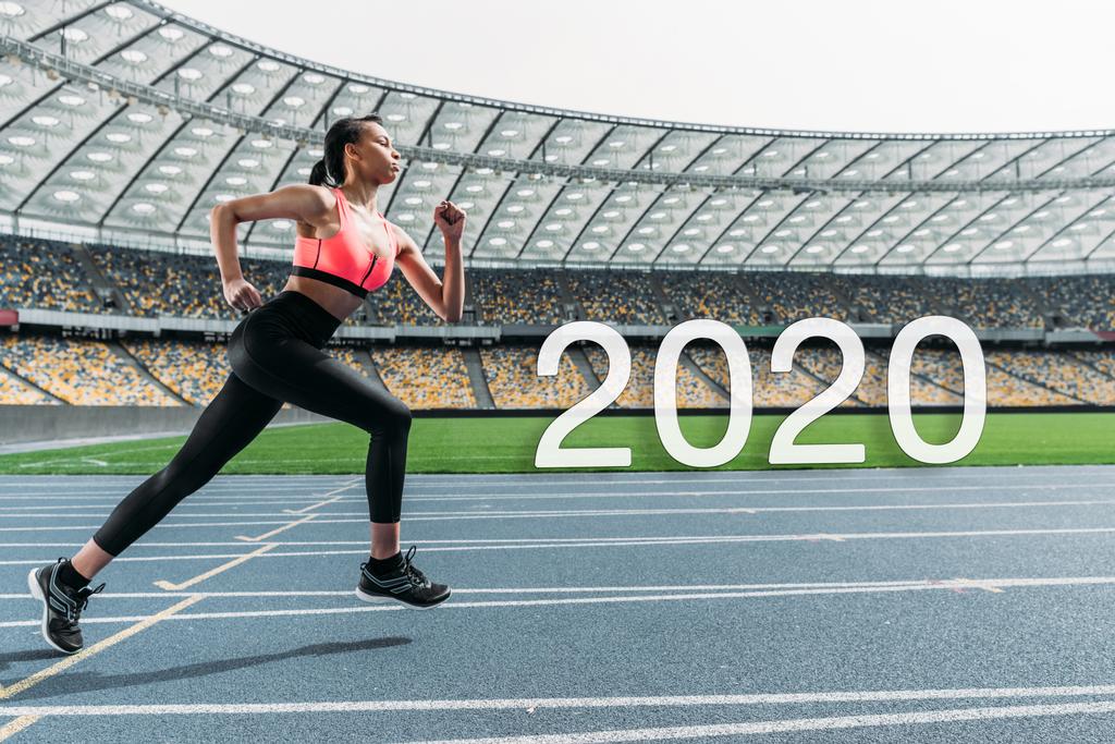 young african american sportswoman running on stadium near 2020 lettering - Photo, Image