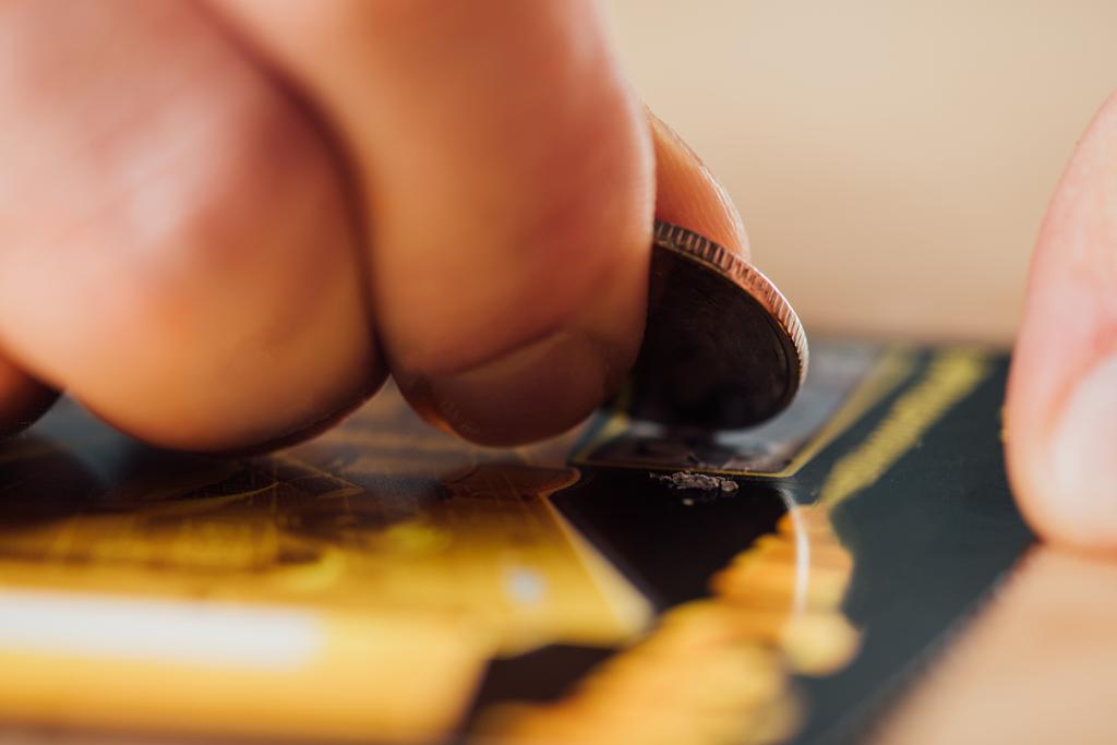 вибірковий фокус срібної монети в руці гравця, що дряпає лотерейний квиток
 - Фото, зображення