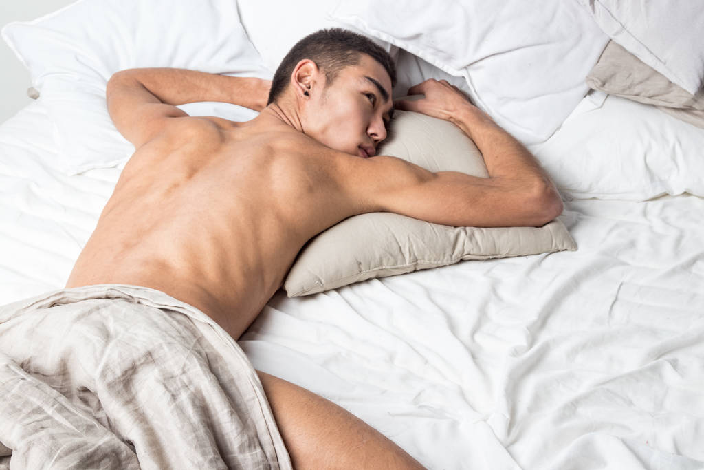 Joven hombre guapo descansar en la cama. Sexy chico desnudo está descansando
 - Foto, Imagen