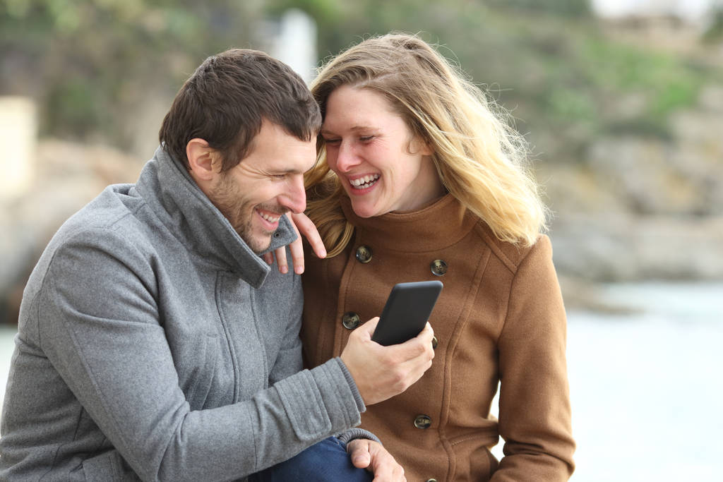 幸せなカップルは電話の内容について話して笑う - 写真・画像