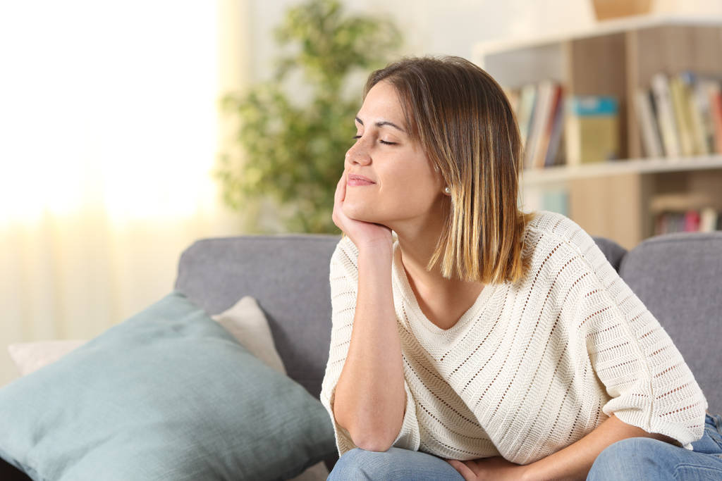 Розслаблена жінка роздумує сидячи на дивані вдома
 - Фото, зображення