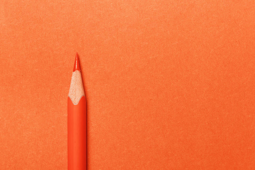 Pomerančová tužka leží na oranžovém papíře na pozadí - Fotografie, Obrázek