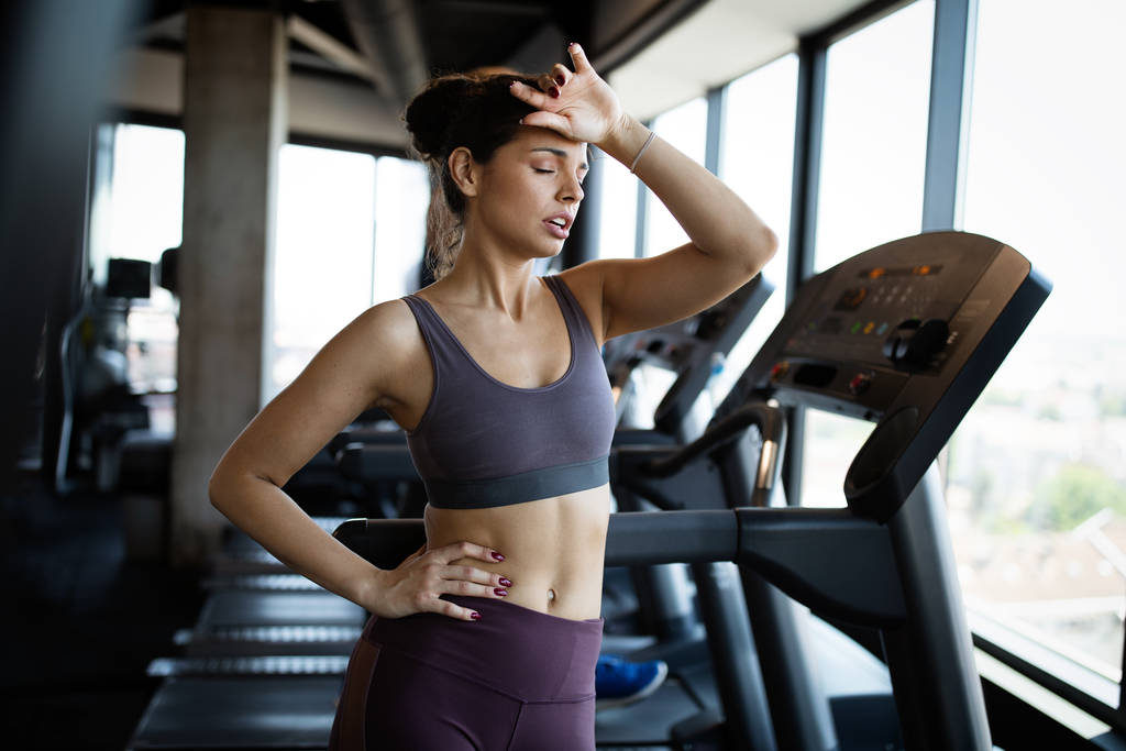 Fitness woman. Beautiful young fit girl in the gym on the treadmill. Fatigue, hand in head, wipes sweat. - Photo, Image