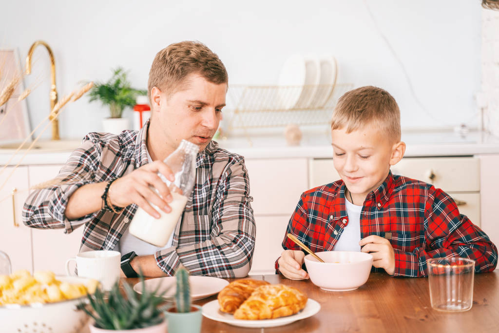 Isä ja poika syövät aamiaista kotona
 - Valokuva, kuva