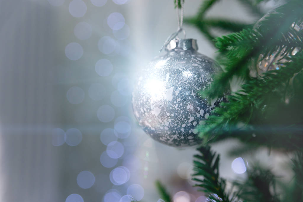 Close up of beautiful christmas decoration - bauble Christmas silver ball hanging on the Christmas tree on the background of blue bokeh. Christmas winter background with bokeh and magic highlights. - Photo, Image