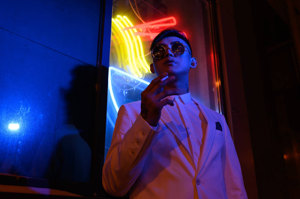 joven asiático hombre en un traje blanco en un fondo de luces de neón
 - Foto, Imagen