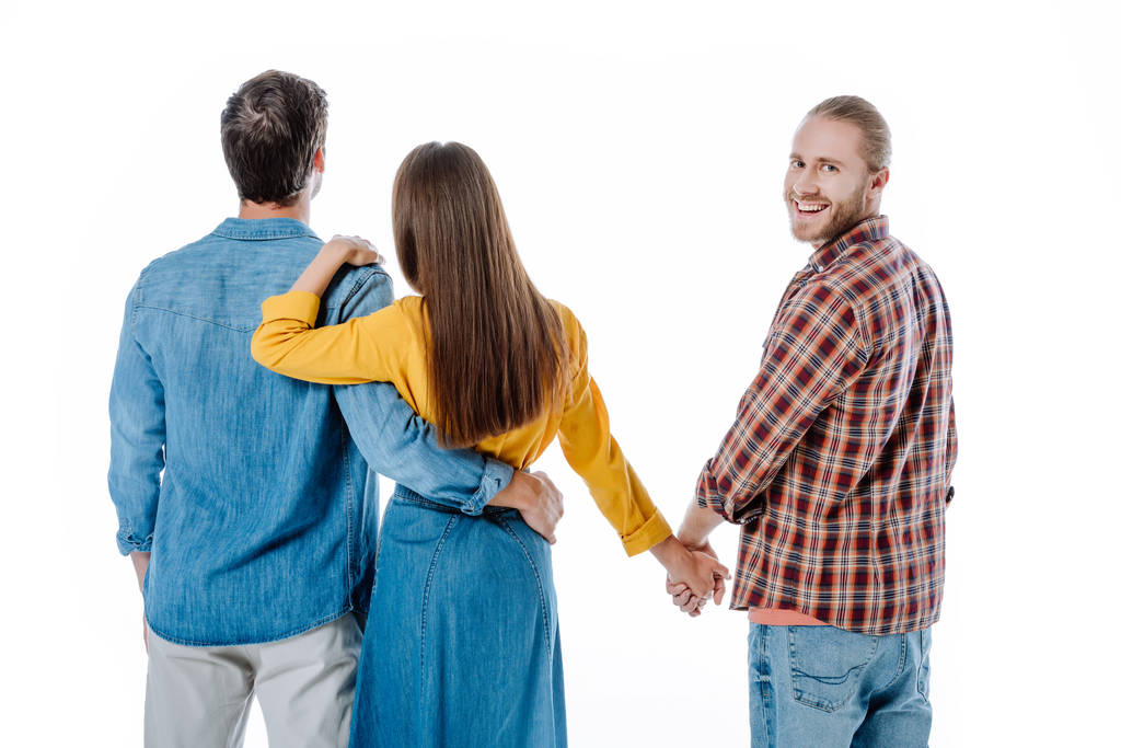 terug uitzicht van paar knuffelen terwijl vrouw hand in hand met een andere man geïsoleerd op wit - Foto, afbeelding