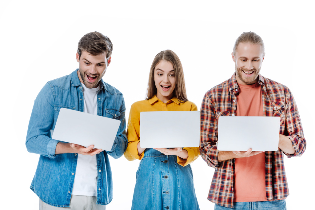 щасливі молоді друзі тримають ноутбуки з відкритими ротами ізольовані на білому
 - Фото, зображення