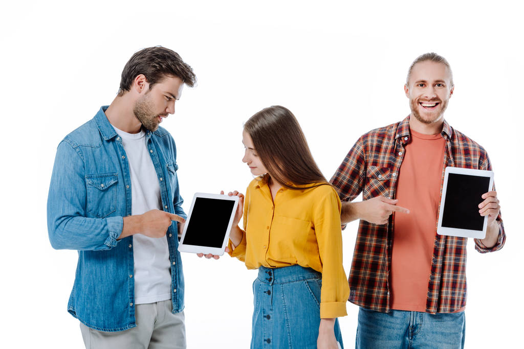 drie jonge vrienden op zoek naar digitale tabletten geïsoleerd op wit - Foto, afbeelding