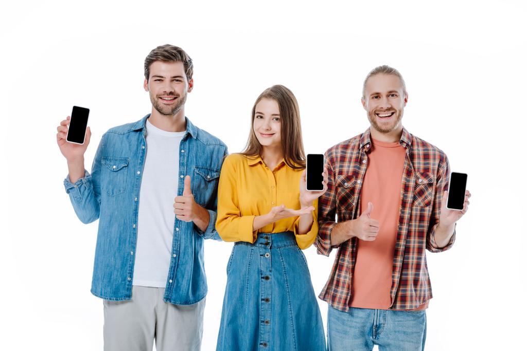 Üç genç arkadaş ellerinde boş ekranlı akıllı telefonlar tutuyorlar ve beyaz ekranda baş parmaklarını gösteriyorlar. - Fotoğraf, Görsel