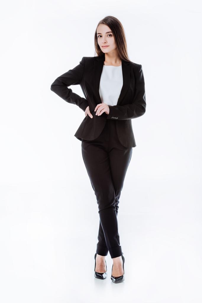 Ganzkörperansicht der selbstbewussten Geschäftsfrau im Anzug posiert mit überkreuzten Beinen isoliert auf weißem Grund - Foto, Bild