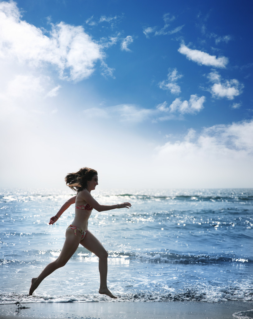 Νεαρή γυναίκα που τρέχει κατά μήκος του ωκεανού - Φωτογραφία, εικόνα