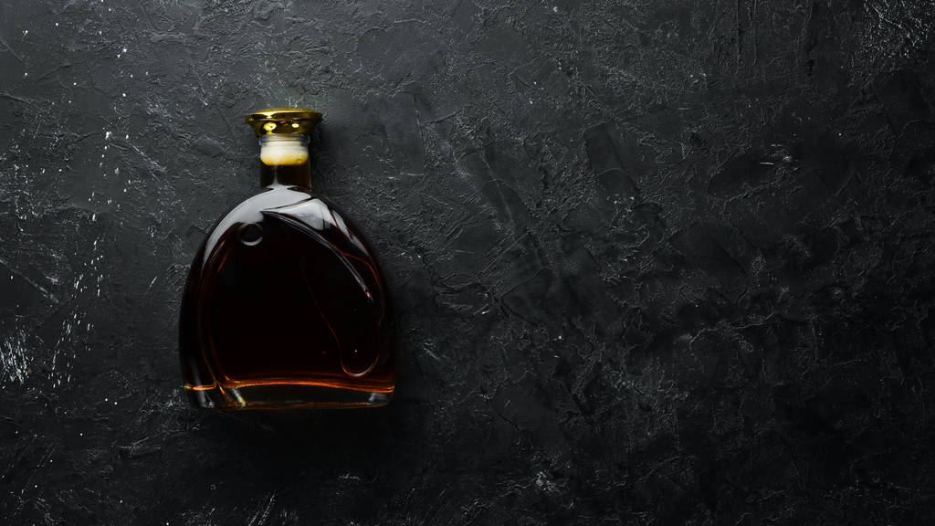 Whisky con coñac en una botella sobre una mesa de piedra negra. Vista superior. Espacio libre para tu texto
. - Foto, imagen