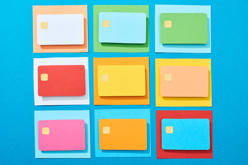 bovenaanzicht van veelkleurige lege creditcards op blauwe achtergrond - Foto, afbeelding