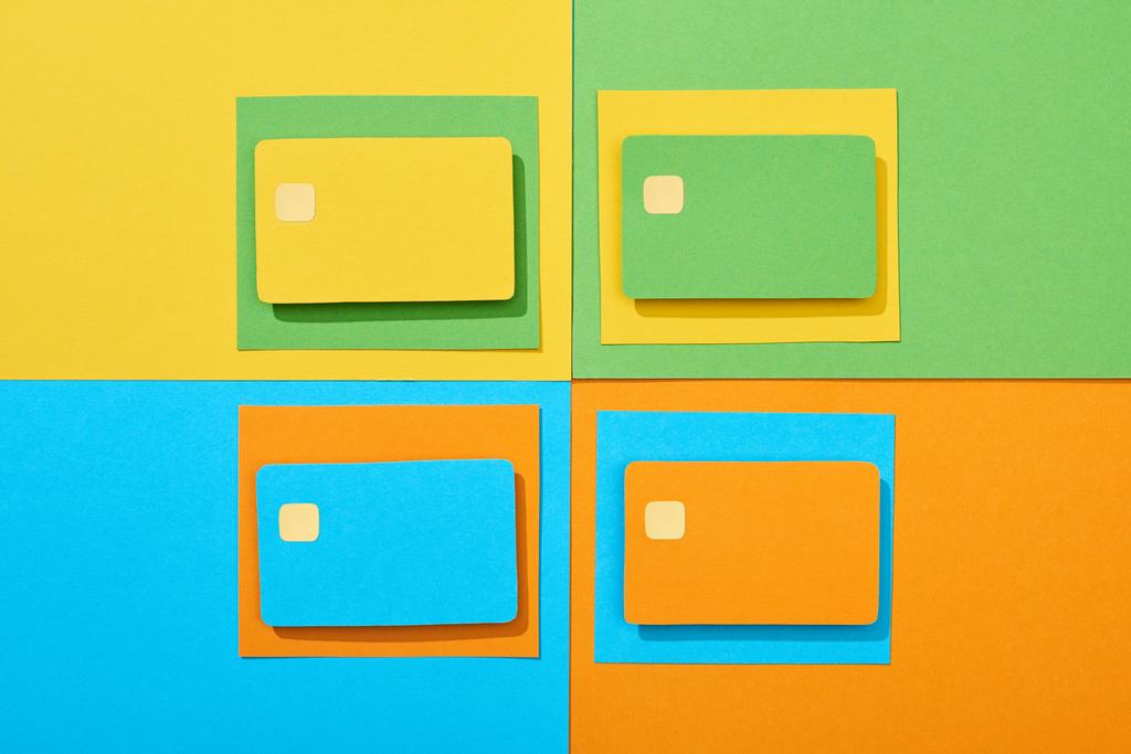 vista superior de las tarjetas de crédito vacías sobre fondo verde, naranja, azul y amarillo
 - Foto, Imagen